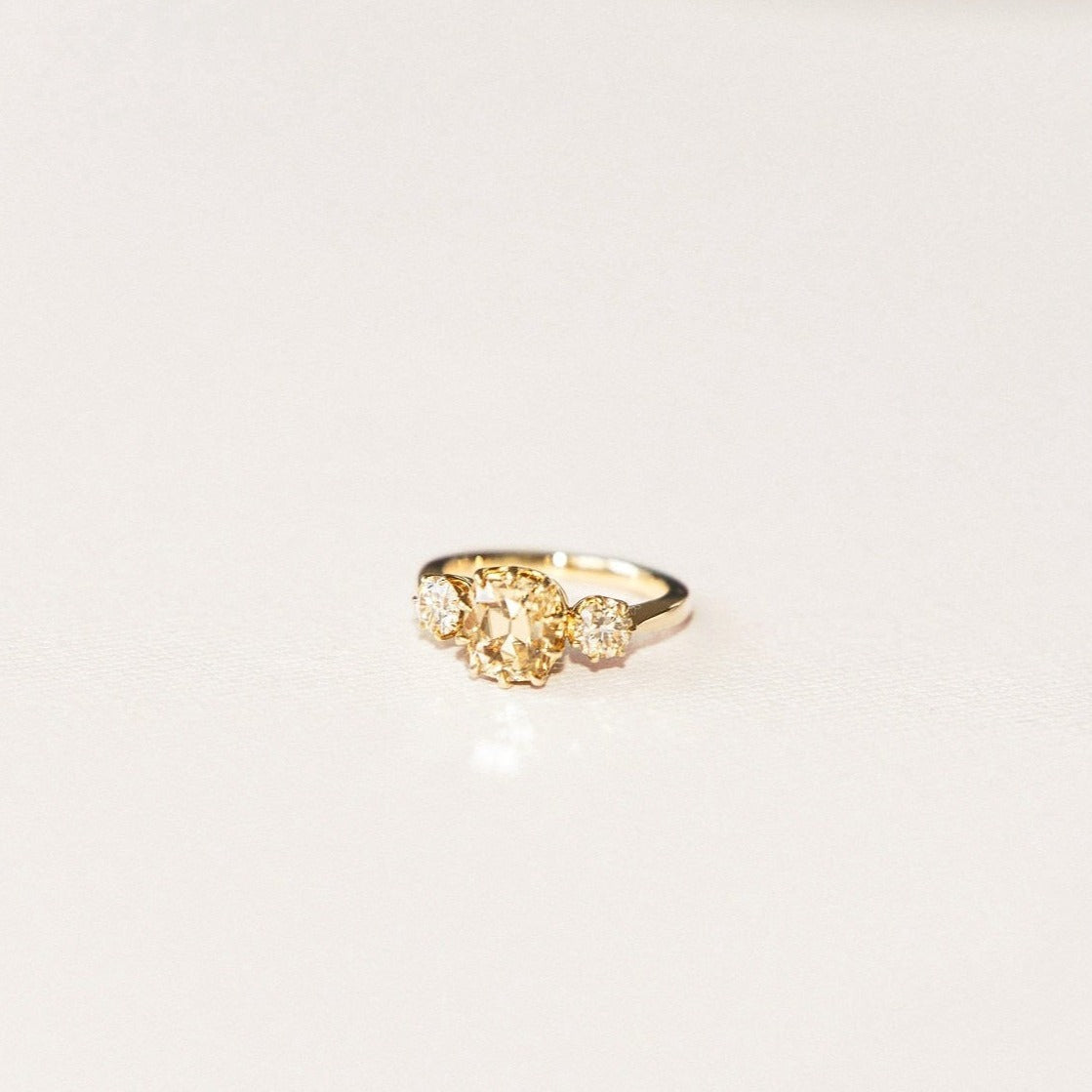 A gold ring featuring a central champagne diamond with bubble-like diamond accents on a white background.