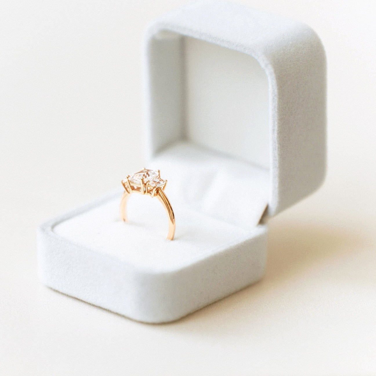 emerald cut sapphire engagement ring with diamond side stones in gold band displayed in white ring box