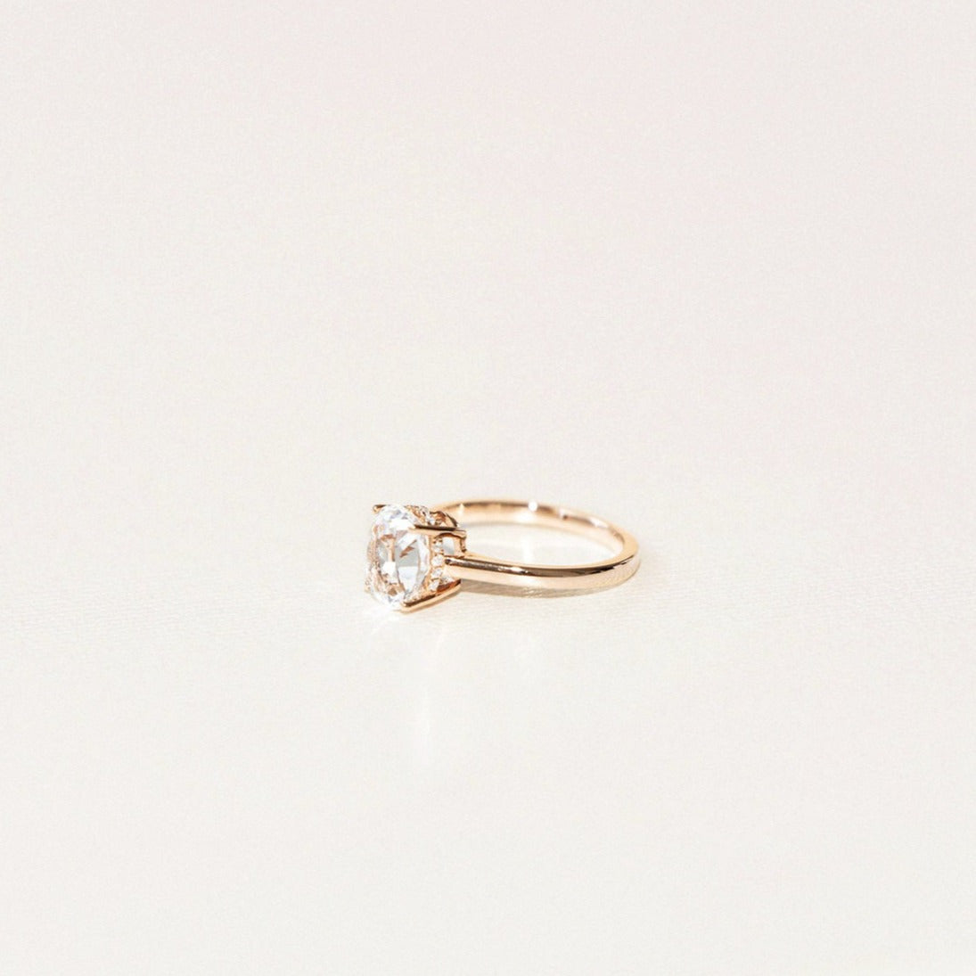 side view of white oval sapphire engagement ring with hidden diamond halo in yellow gold