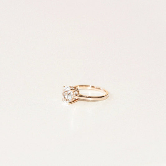 side view of white oval sapphire engagement ring with hidden diamond halo in yellow gold