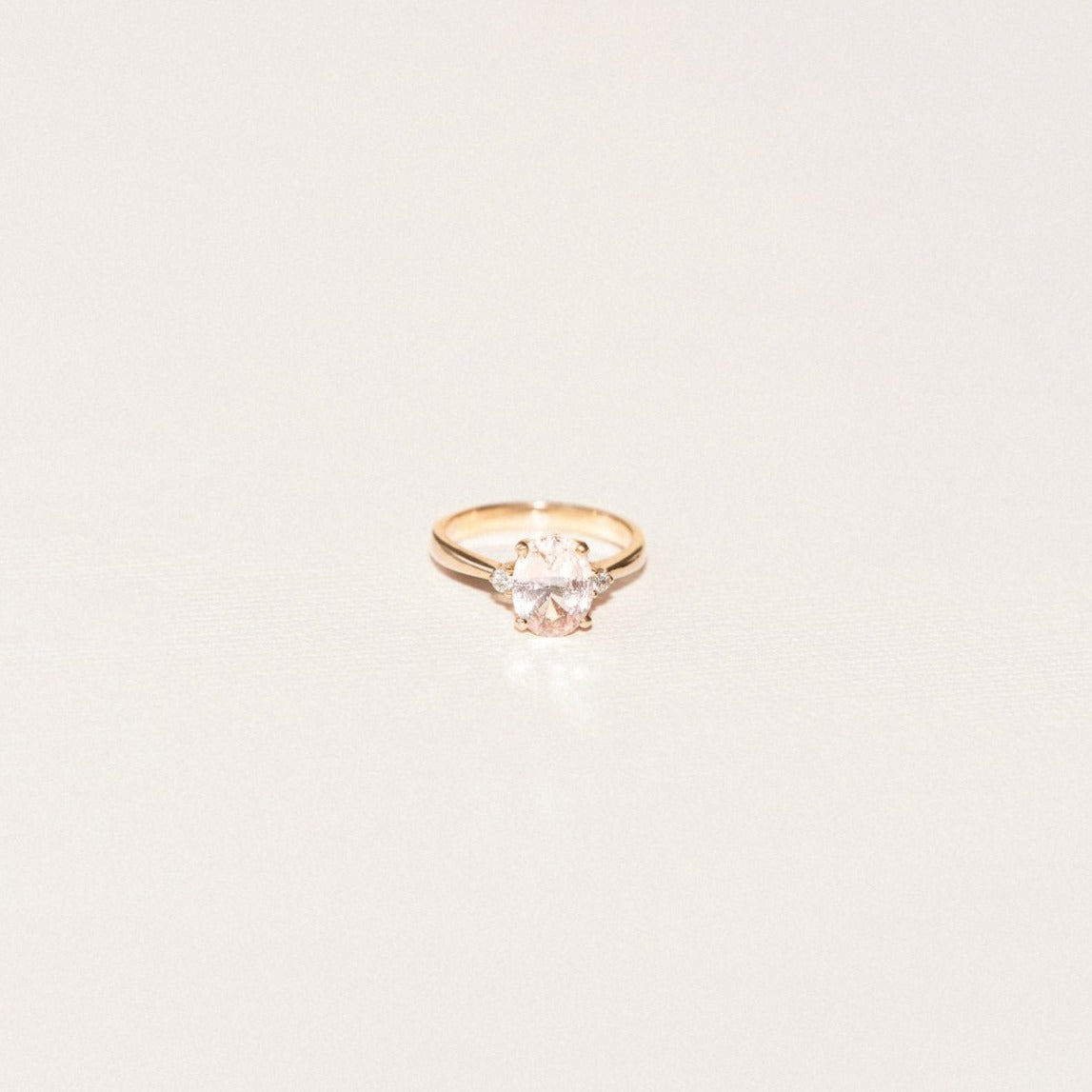 Oval sapphire engagement ring with two side diamonds in a three-stone setting.