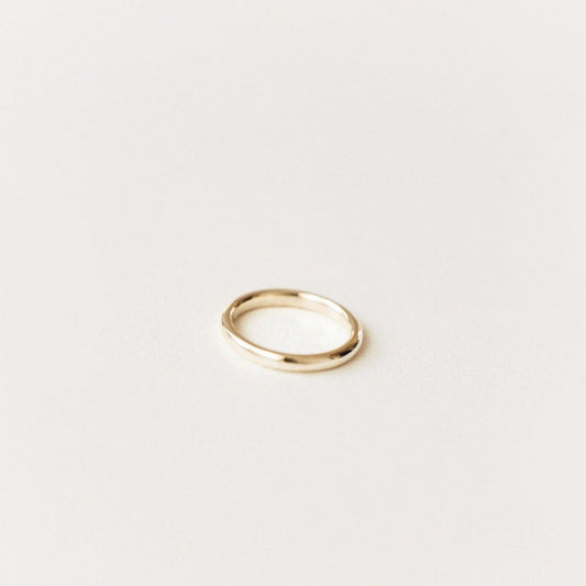 A gold band ring on a white background.