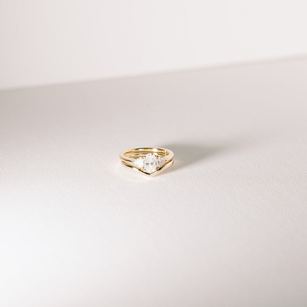 Veil curved wedding band stacked with Euphoric diamond engagement ring in yellow gold.
