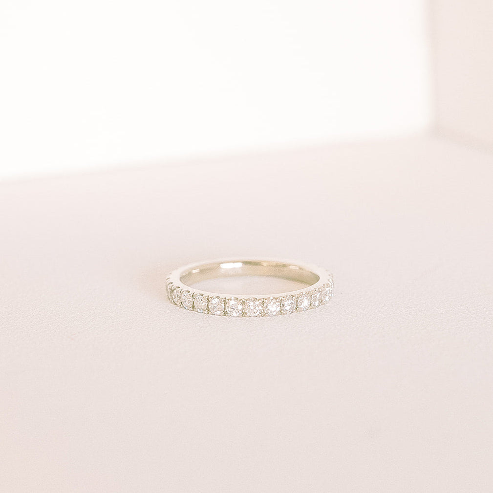Betrothed — eternity diamond wedding band in white gold, low side view on soft background.