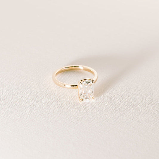 Heirloom old mine cut cushion diamond ring in yellow gold, angled view on light background.