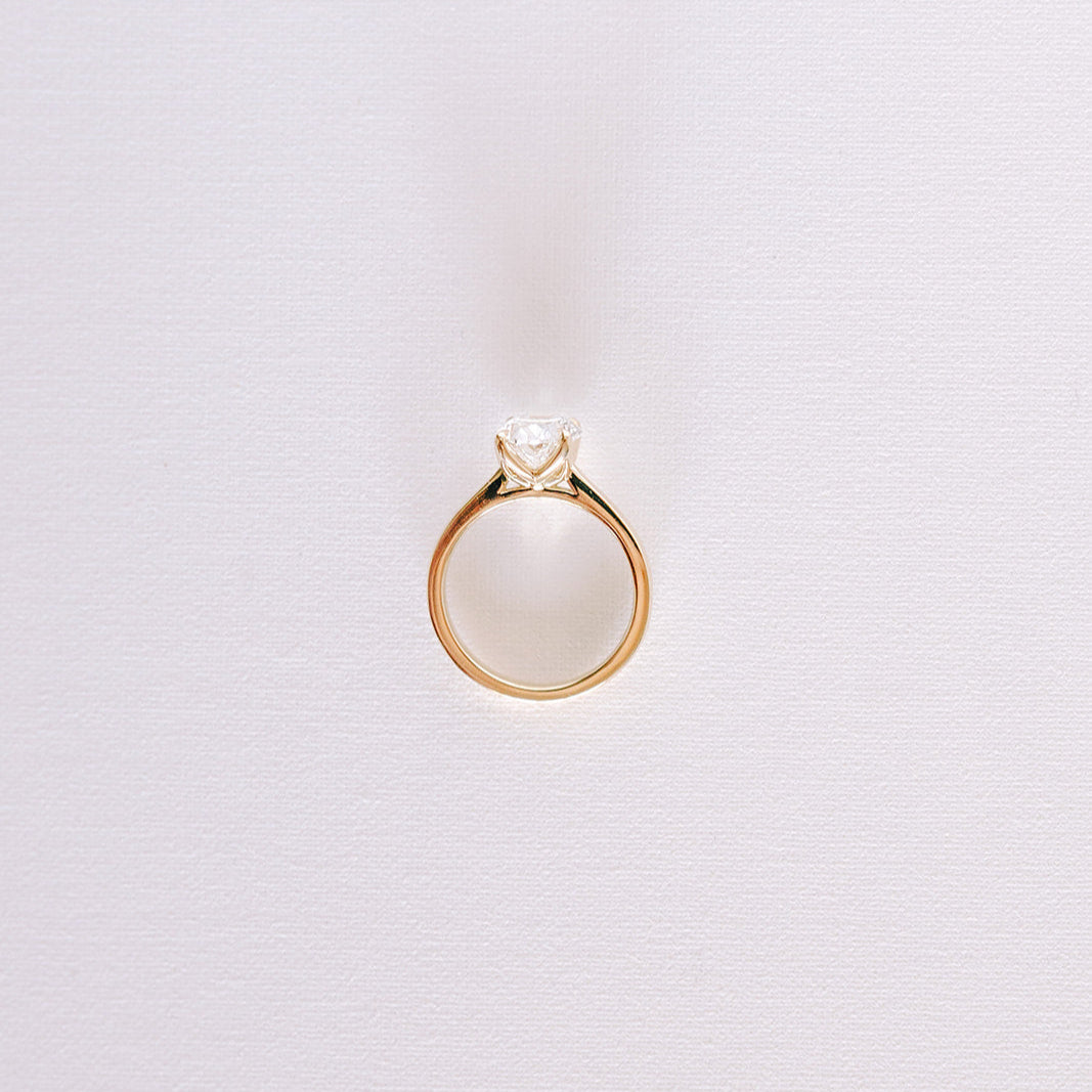 Oval lab-grown diamond engagement ring in yellow gold cathedral setting, front view against light background.