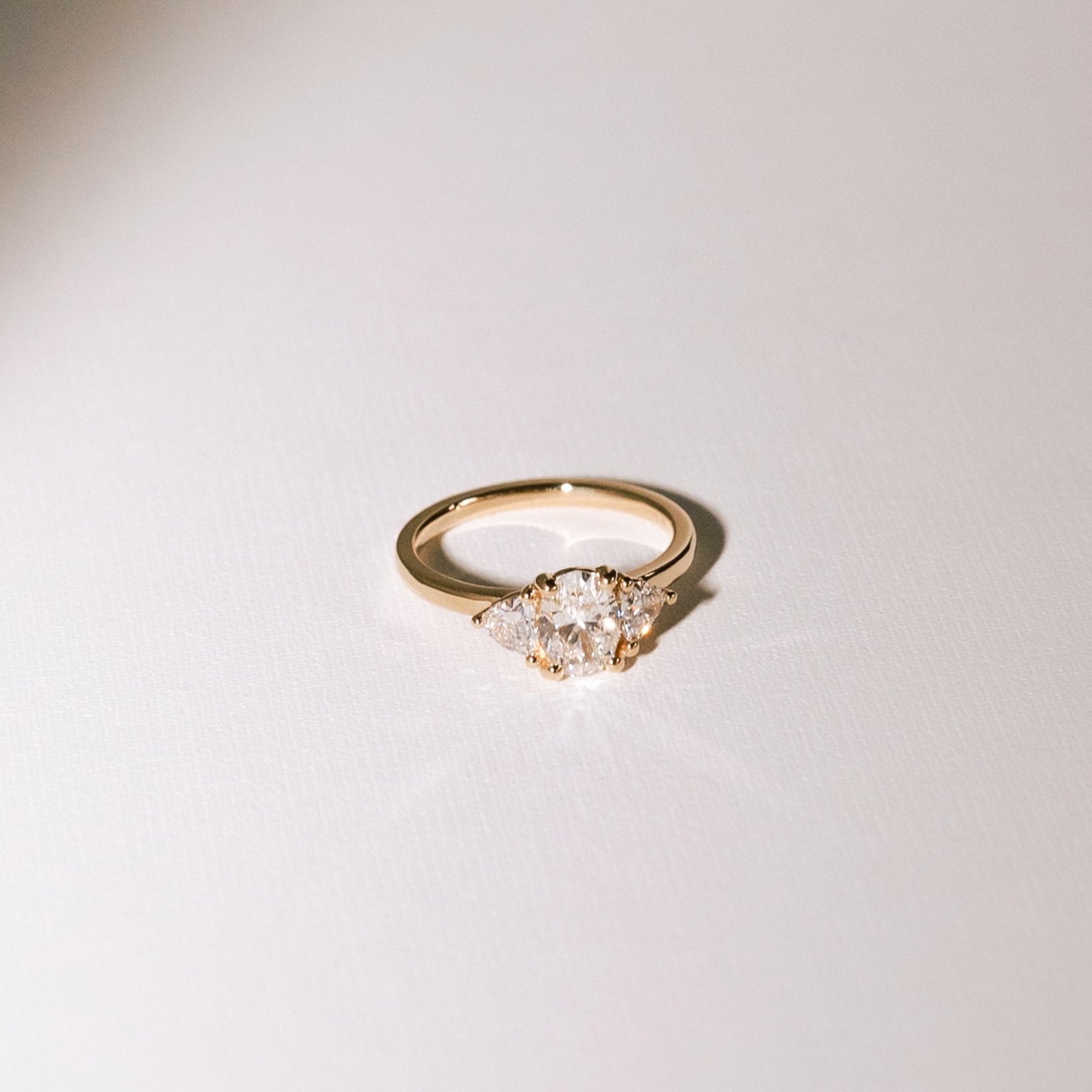 Euphoric High three-stone engagement ring with oval lab diamond and trilliant side diamonds in 14k yellow gold.