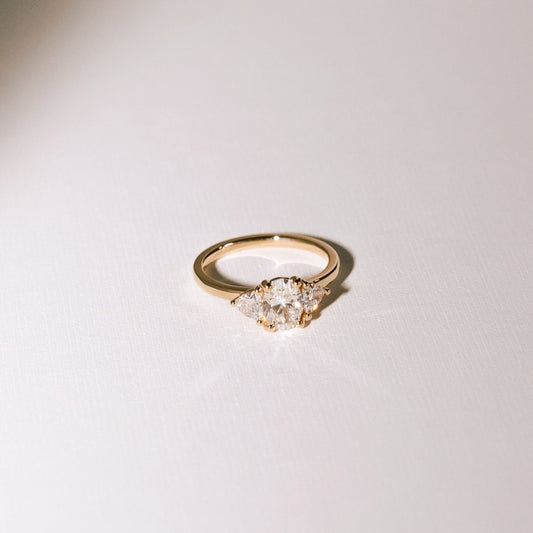 Euphoric High three-stone engagement ring with oval lab diamond and trilliant side diamonds in 14k yellow gold.