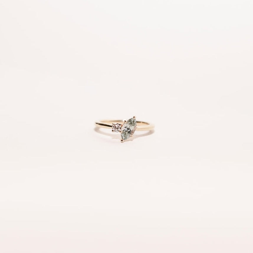 Moonlit Tide toi et moi ring featuring a marquise green sapphire and round diamond set on a slim gold band, front angle.