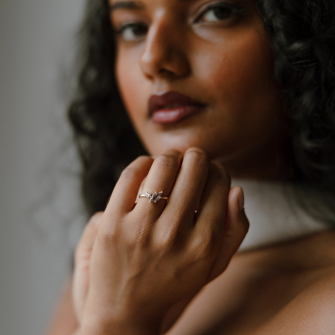 Pink marquise sapphire and round diamond toi et moi engagement ring in 14k yellow gold, shown on model’s hand.