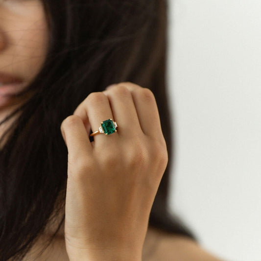 emerald cut emerald engagement ring with trapezoid diamond side stones in yellow gold
