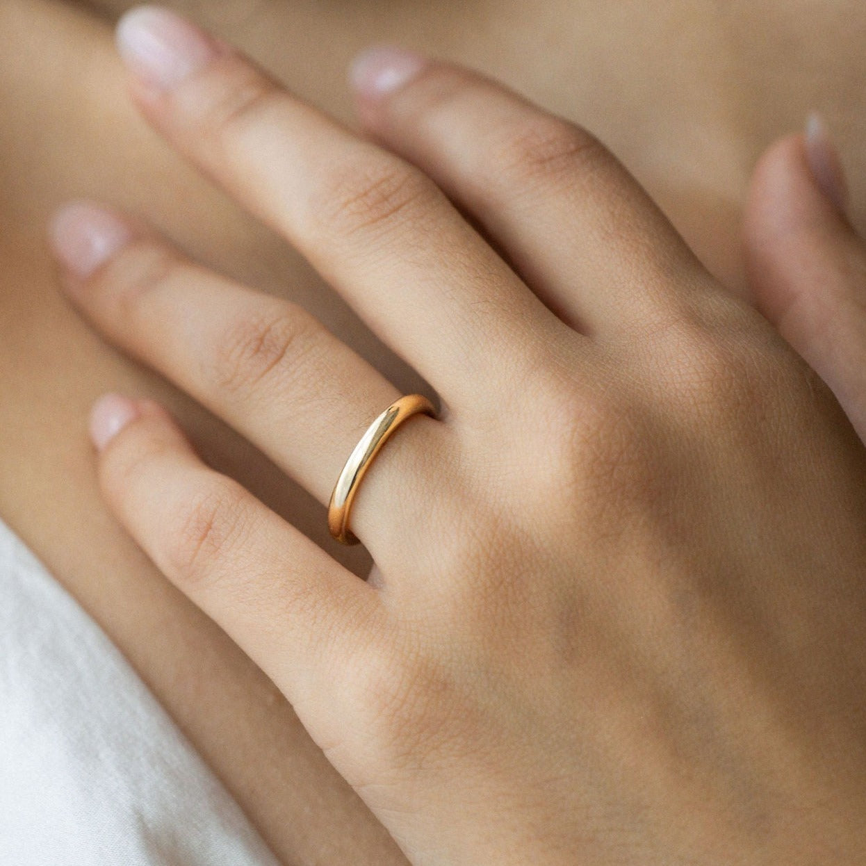 Hitched classic 14k yellow gold wedding band shown on hand, simple and timeless in design.