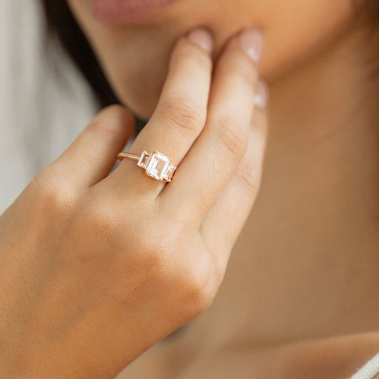 Emerald cut sapphire engagement ring with diamond baguette side stones in yellow gold.