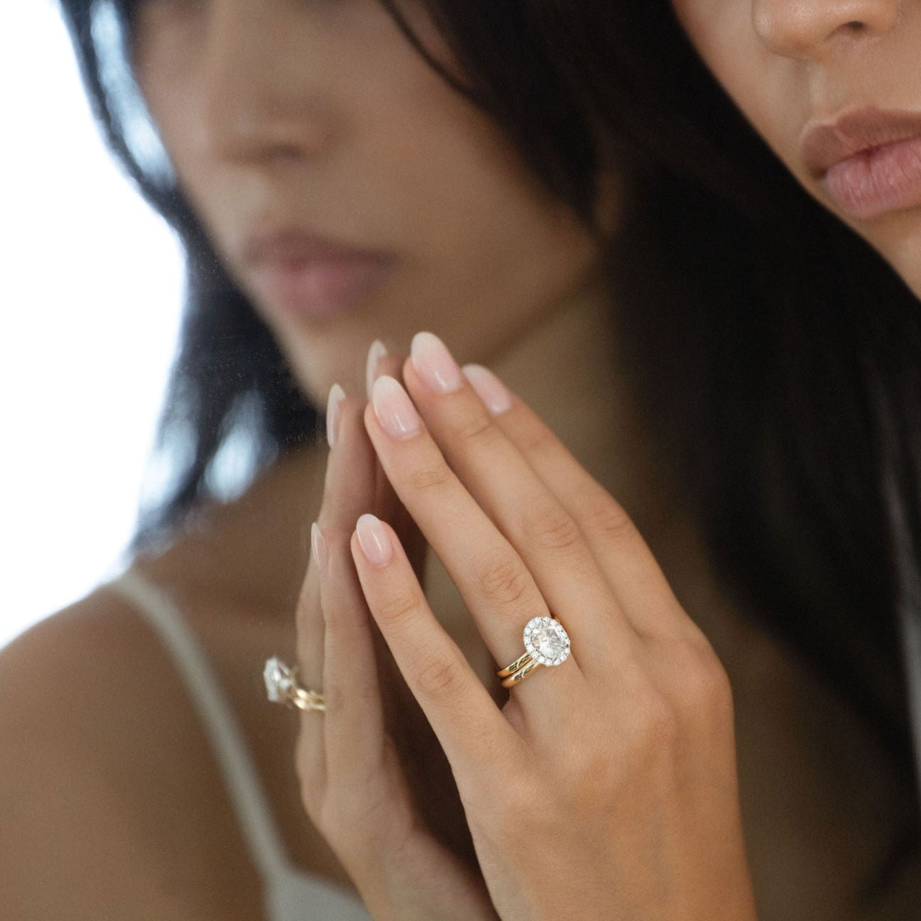Oval white sapphire engagement ring with diamond halo in gold.