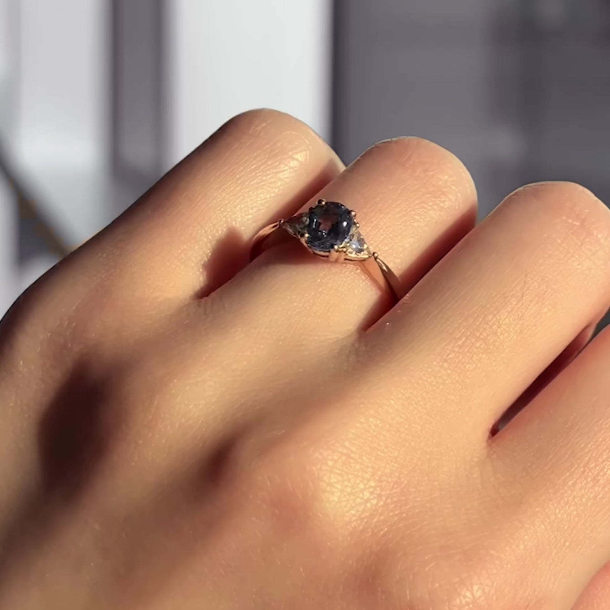 Hand wearing the Euphoric Teal trilogy ring featuring a natural teal sapphire centre stone with two trilliant-cut lab diamond side stones, set in a yellow gold band.