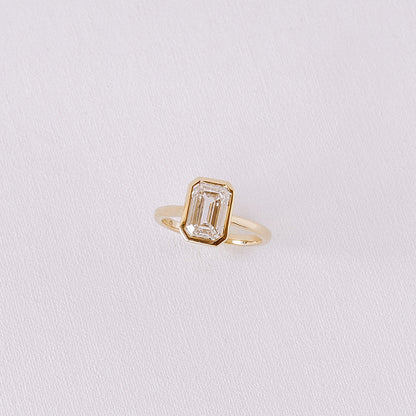 Ma Folie emerald-cut bezel lab diamond engagement ring in 14k yellow gold shown at an angle highlighting the clean bezel setting and diamond facets