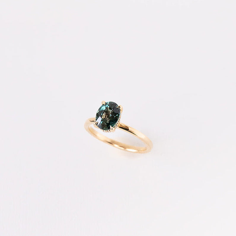 Gold ring with a teal green sapphire 