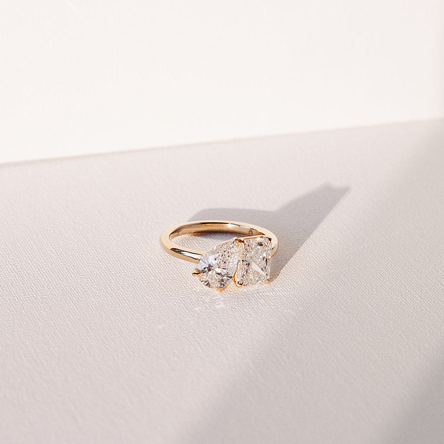 toi et moi gold ring with pear and radiant lab diamonds shown in direct sunlight with shadow