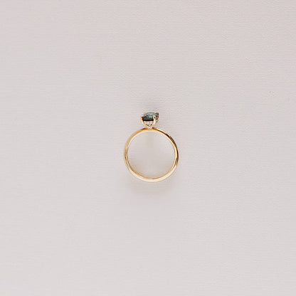 Top-down view of the Sweet Romance teal sapphire ring, highlighting the full 14k yellow gold band and a glimpse of the hidden diamond halo.