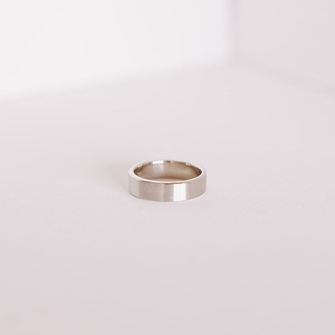 Side view of the Vow (Brushed) men’s wedding band lying flat, showing the smooth interior and brushed 14k white gold exterior.