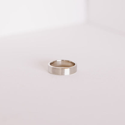 Side view of the Vow (Brushed) men’s wedding band lying flat, showing the smooth interior and brushed 14k white gold exterior.
