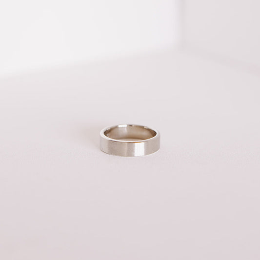 Side view of the Vow (Brushed) men’s wedding band lying flat, showing the smooth interior and brushed 14k white gold exterior.