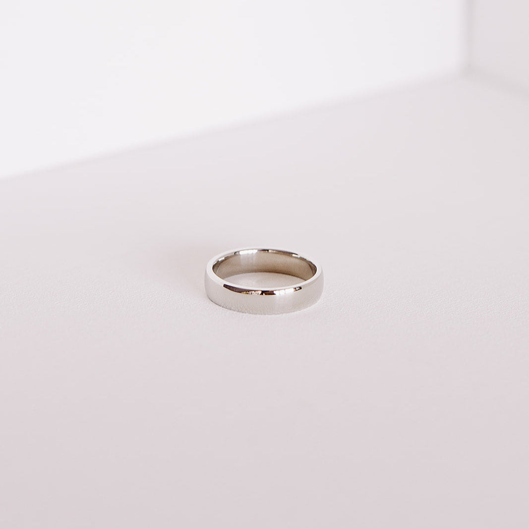 Front angle of the Espoused men’s wedding band in 14k white gold, showing the classic low-dome shape and high polish finish on a soft neutral background.
