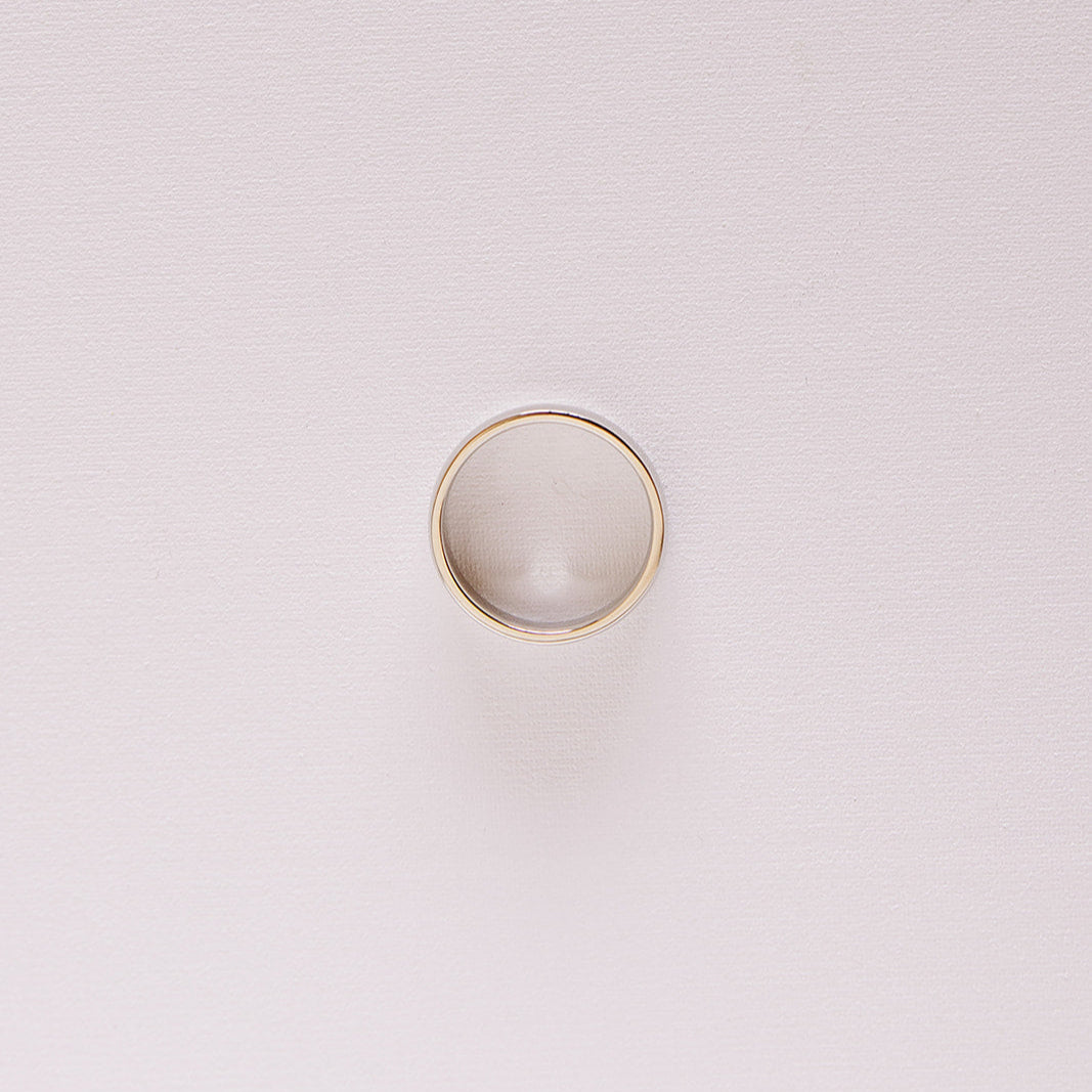 Top-down view of the Espoused men’s wedding band in 14k white gold, laying on it's side highlighting the classic low-dome profile and high polish finish.