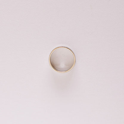 Top-down view of the Espoused men’s wedding band in 14k white gold, laying on it's side highlighting the classic low-dome profile and high polish finish.
