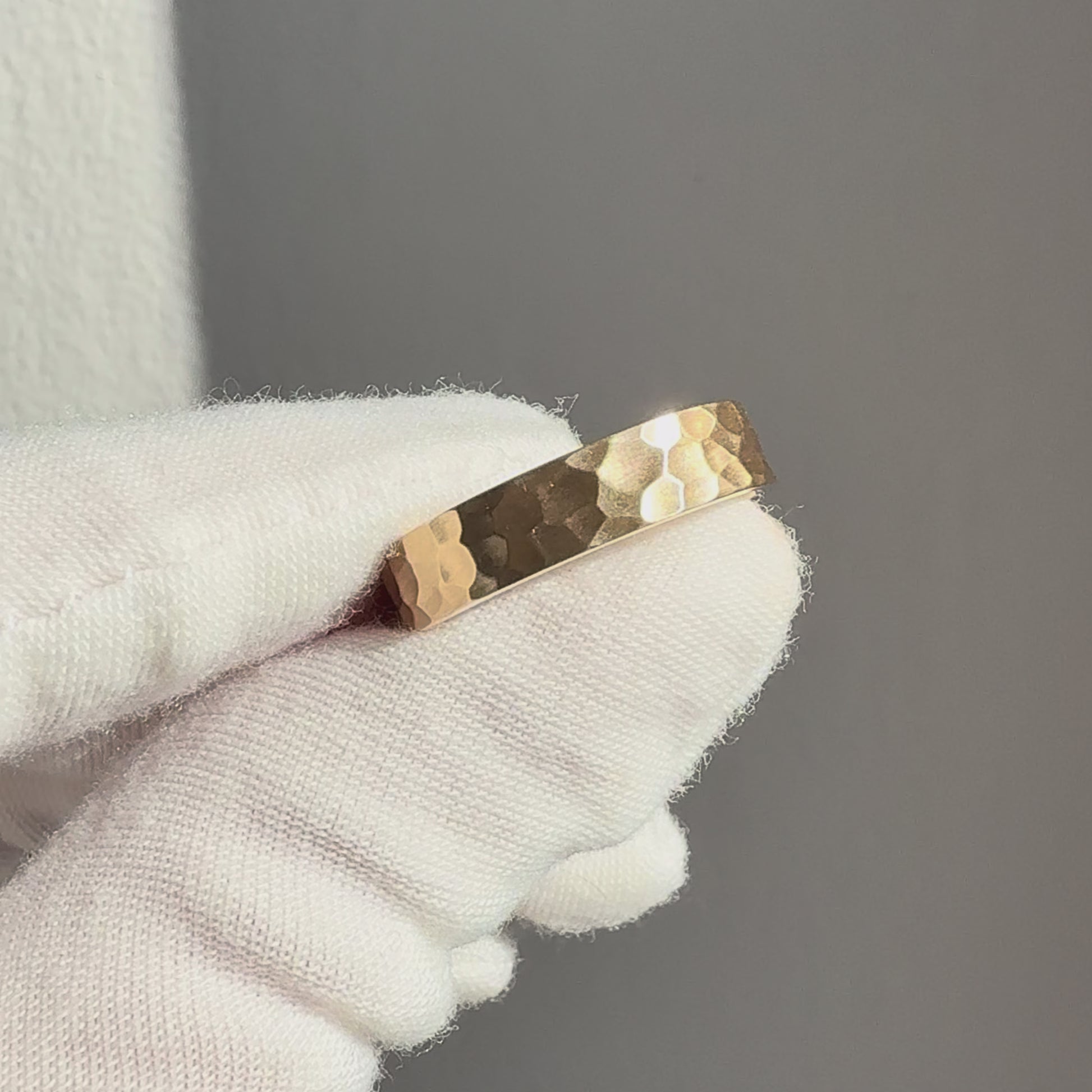 Hammered 6mm men’s wedding band in solid gold with brushed finish showing texture and light in motion