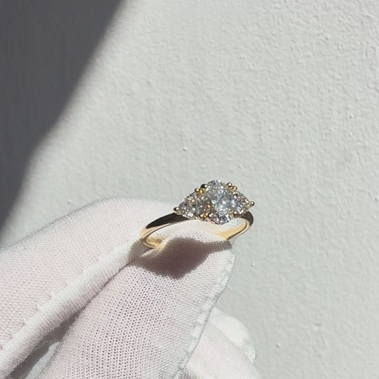Three stone lab diamond ring in 14k yellow gold with oval centre and trilliant side stones showing sparkle and angles in natural light